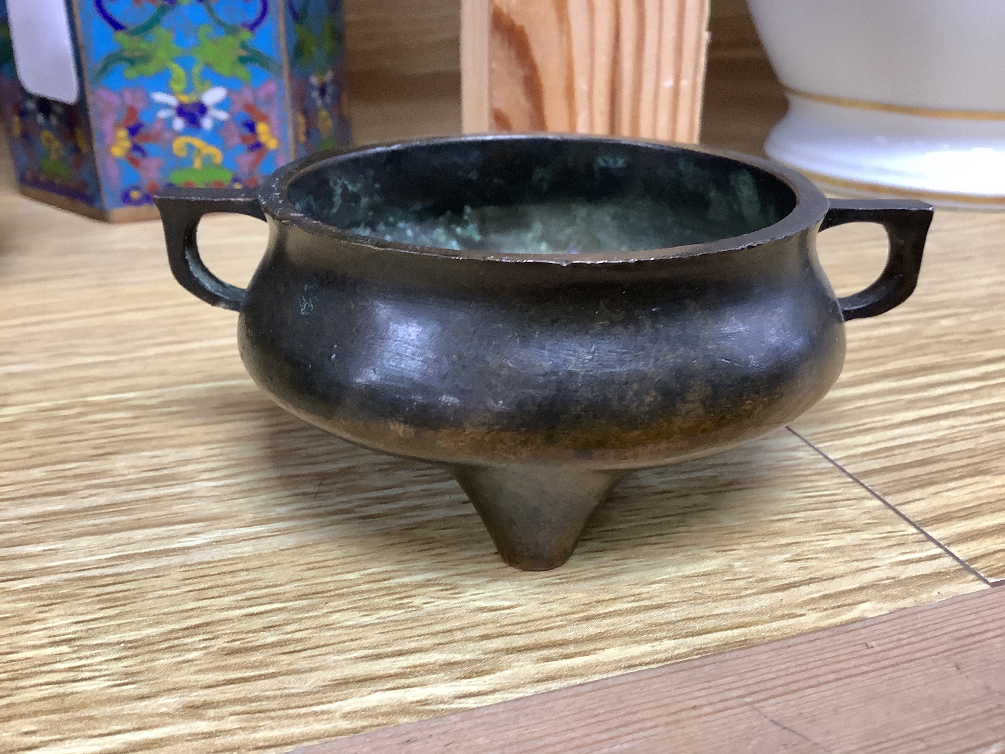 A Chinese small bronze tripod censer, a Chinese archaistic bronze tripod vessel, a bronze jar and cover and a cloisonné enamel wine warming pot